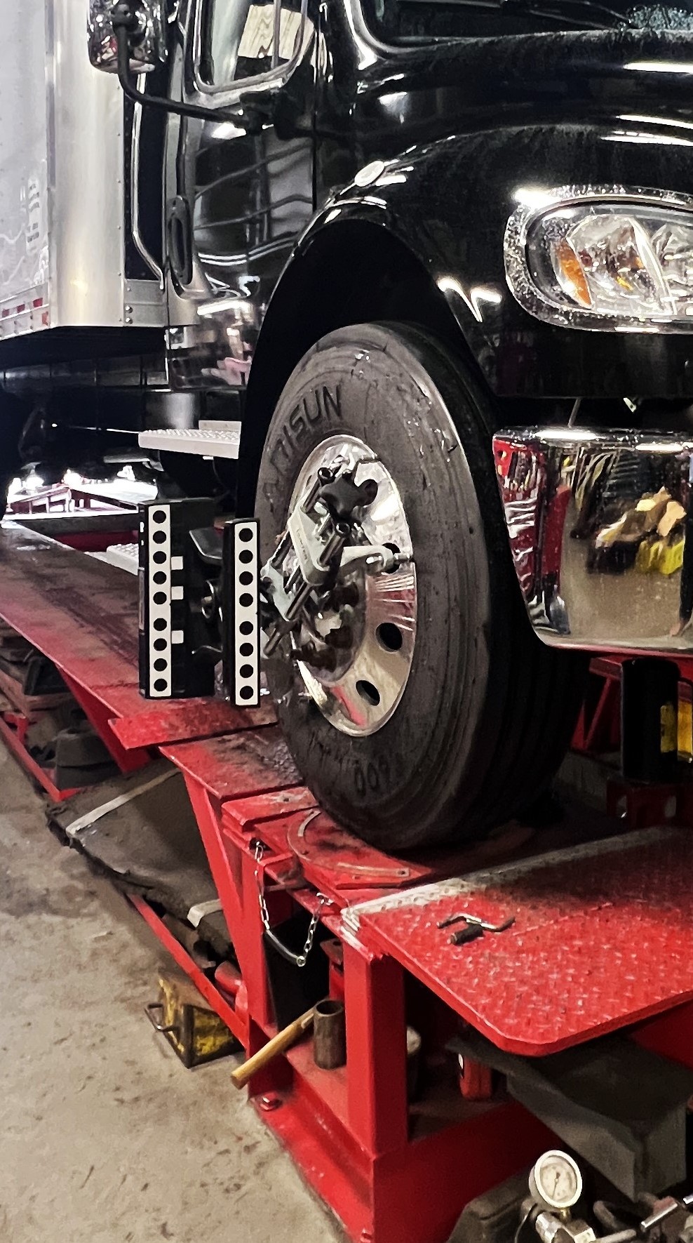 Close-up of a heavy-duty truck wheel with a Hunter alignment sensor clamp attached on the alignment rack